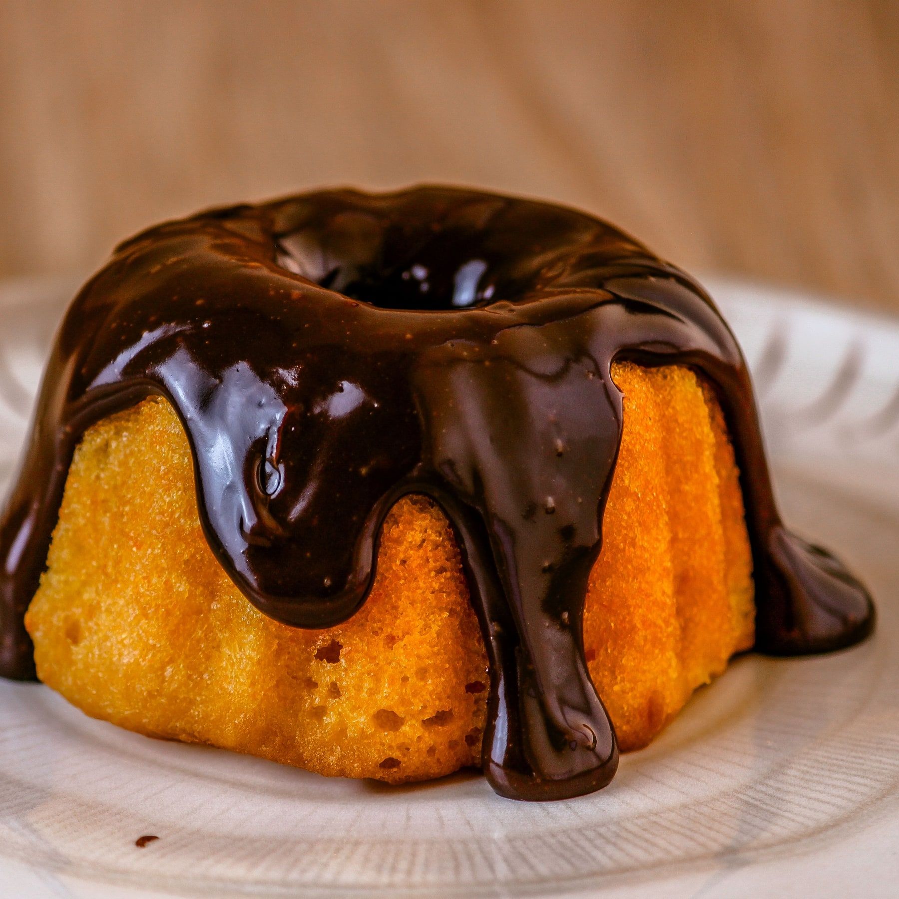 Mini bolo de cenoura com calda de chocolate escorrendo, num prato branco