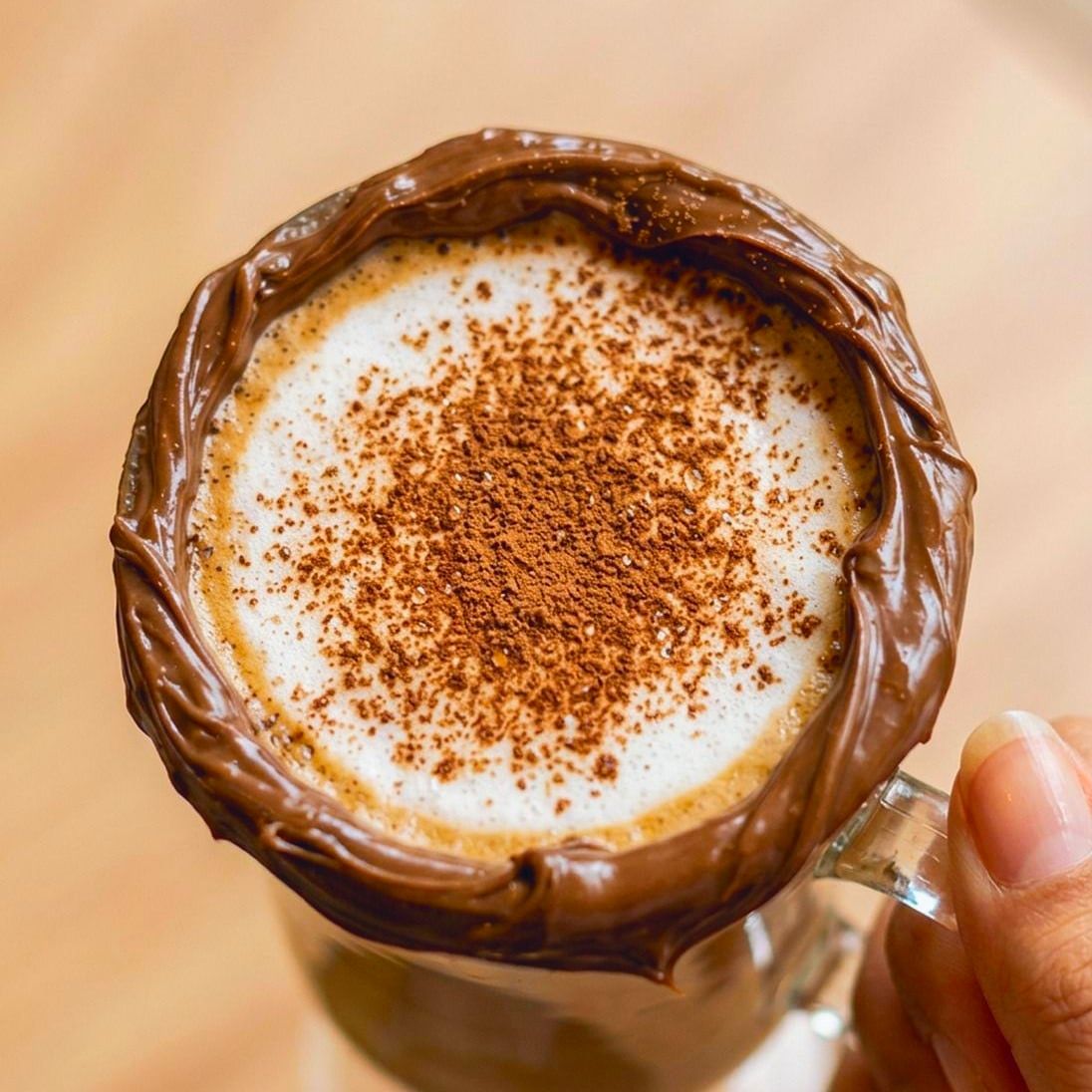 Mocca Nutella na caneca de vidro com a borda coberta de Nutella e cacau em pó sobre a espuma