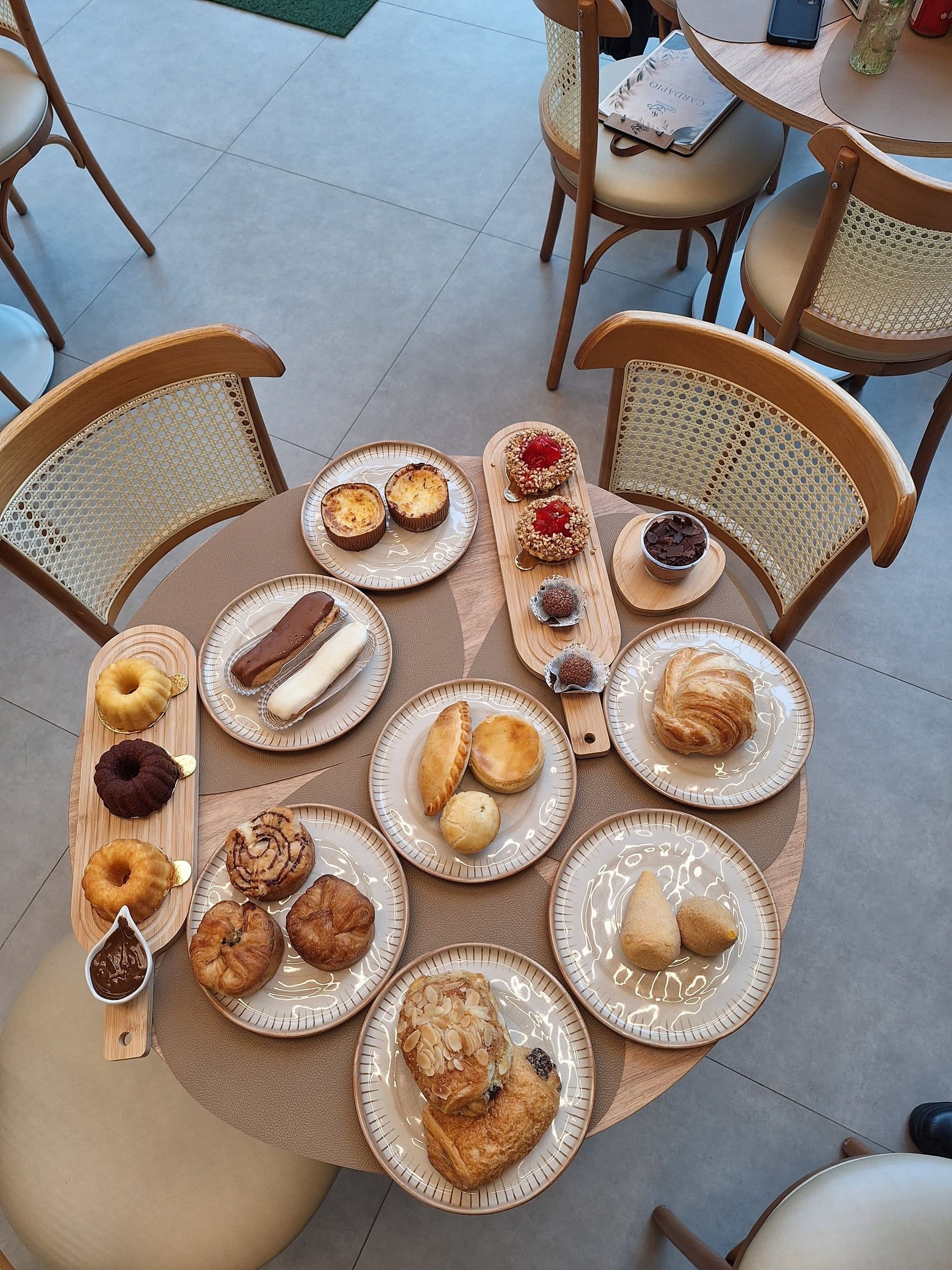 Mesa posta com cafés, doces e salgados, vista de cima